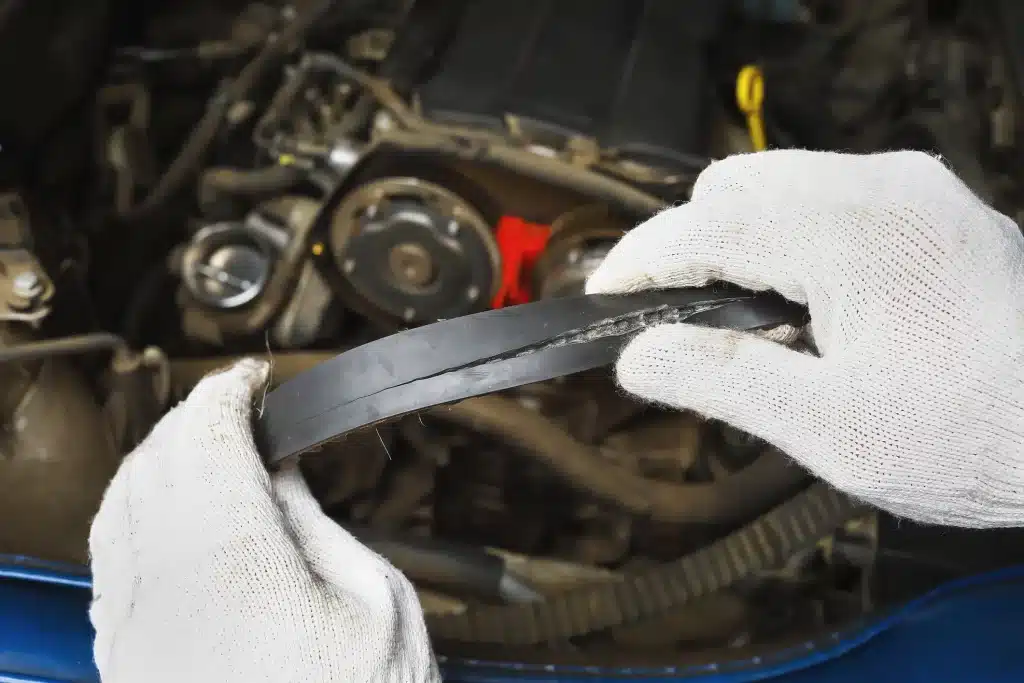 Mechaniker prüft den Zahnriemen eines Automotors nach einem Zahnriemenschaden