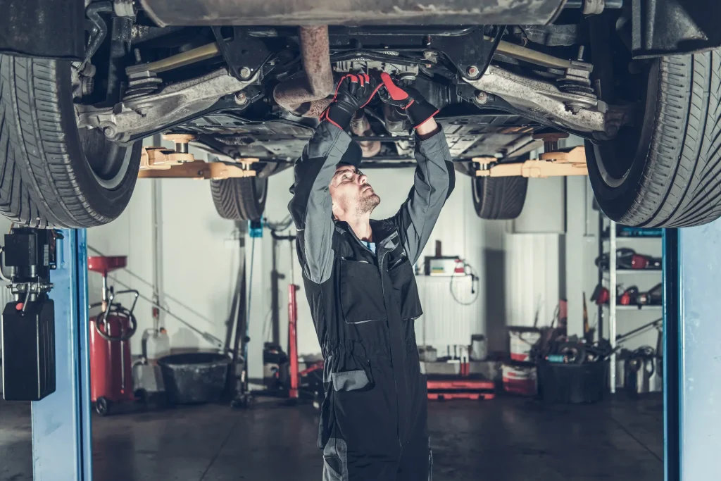 Mechaniker prüft Fahrzeug von unten – typische Anzeichen für Getriebeschaden.